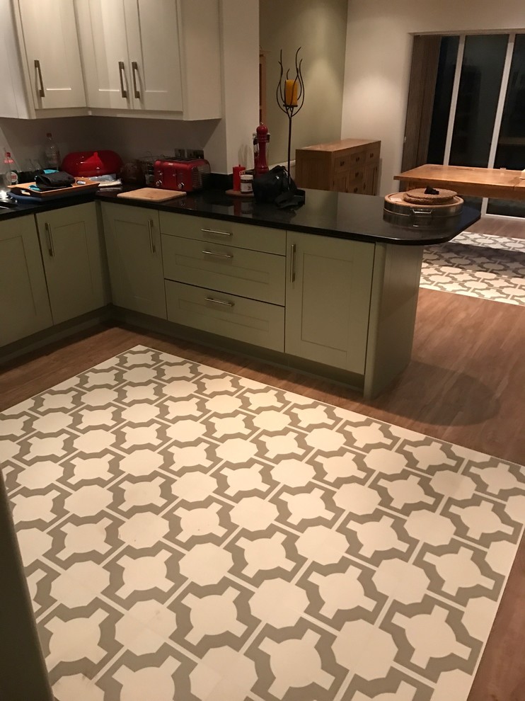 Example of a mid-sized trendy galley vinyl floor and beige floor eat-in kitchen design in Manchester with green cabinets, no island and black countertops