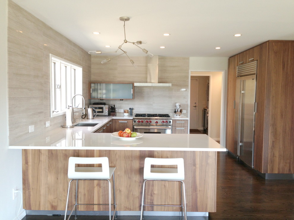 Moderne Küche in U-Form mit flächenbündigen Schrankfronten, Küchengeräten aus Edelstahl, hellbraunen Holzschränken, Küchenrückwand in Beige und Kalk-Rückwand