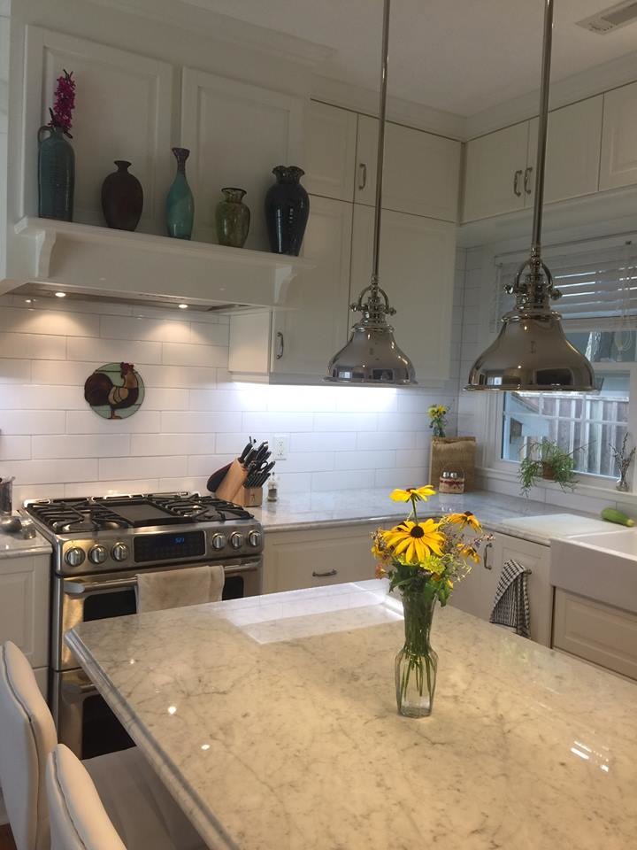 Inredning av ett amerikanskt mellanstort kök, med en rustik diskho, vita skåp, marmorbänkskiva, vitt stänkskydd, stänkskydd i tunnelbanekakel, rostfria vitvaror, mellanmörkt trägolv och en köksö
