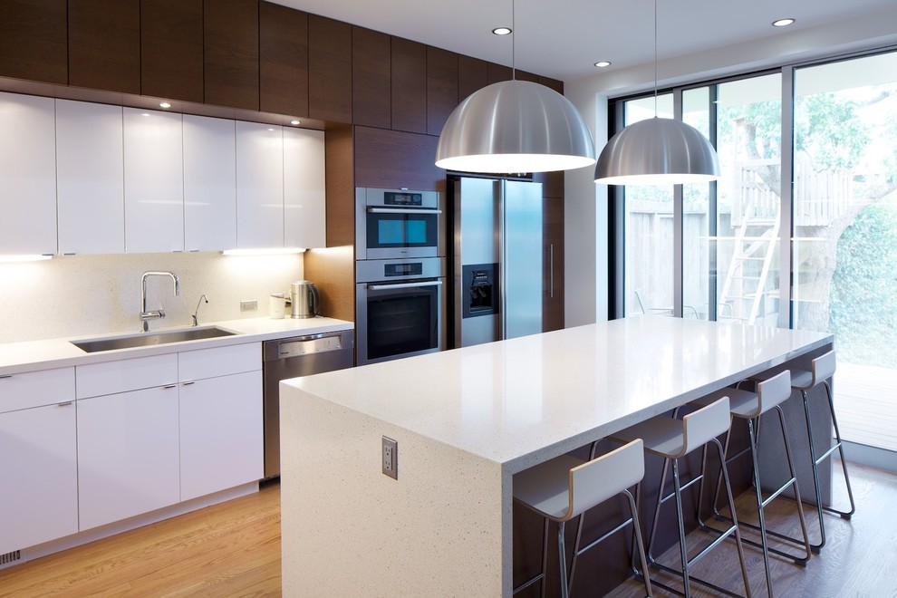 Photo of a modern kitchen in Other with stainless steel appliances, a single-bowl sink, flat-panel cabinets, white cabinets and engineered stone countertops.