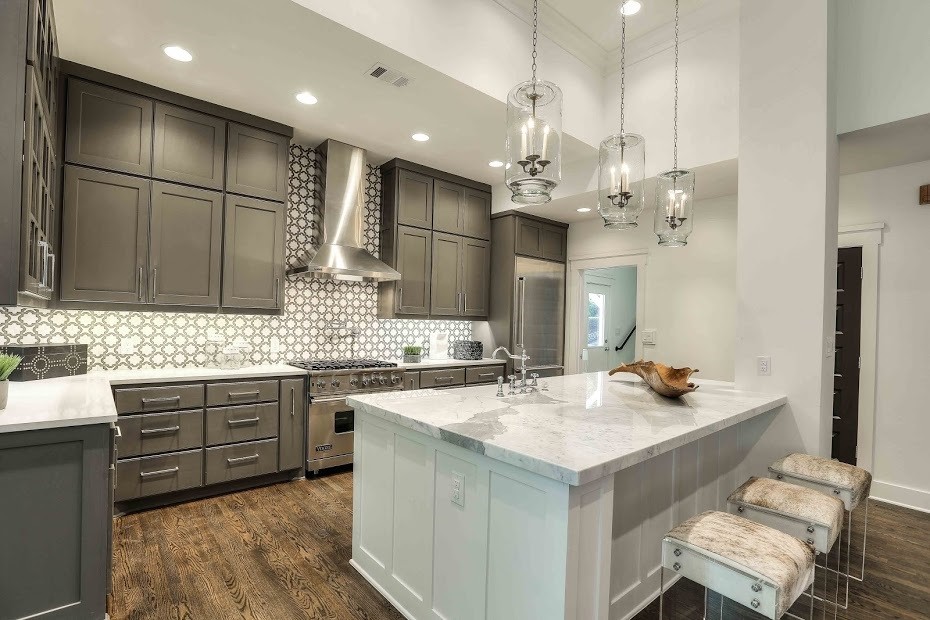 Open concept kitchen - large transitional l-shaped dark wood floor open concept kitchen idea in Austin with a farmhouse sink, shaker cabinets, gray cabinets, marble countertops, gray backsplash, ceramic backsplash, stainless steel appliances and an island