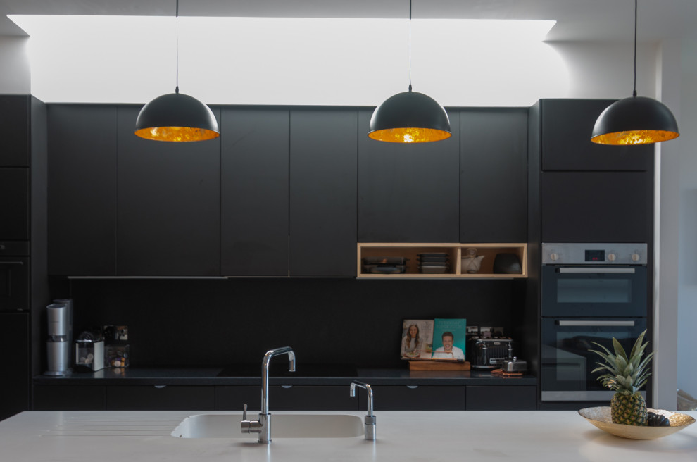 Foto de cocina minimalista con fregadero encastrado, armarios con paneles lisos, salpicadero negro, electrodomésticos negros, una isla, suelo multicolor, encimeras grises y puertas de armario negras