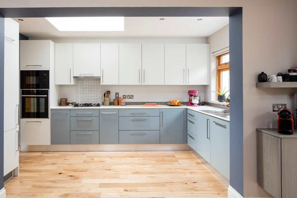 Diseño de cocina contemporánea con fregadero de doble seno, armarios con paneles lisos, puertas de armario azules, encimera de acrílico y suelo de madera clara