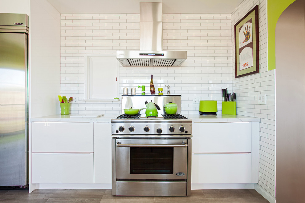 Imagen de cocina contemporánea con armarios con paneles lisos, puertas de armario blancas, salpicadero blanco, salpicadero de azulejos tipo metro y electrodomésticos de acero inoxidable
