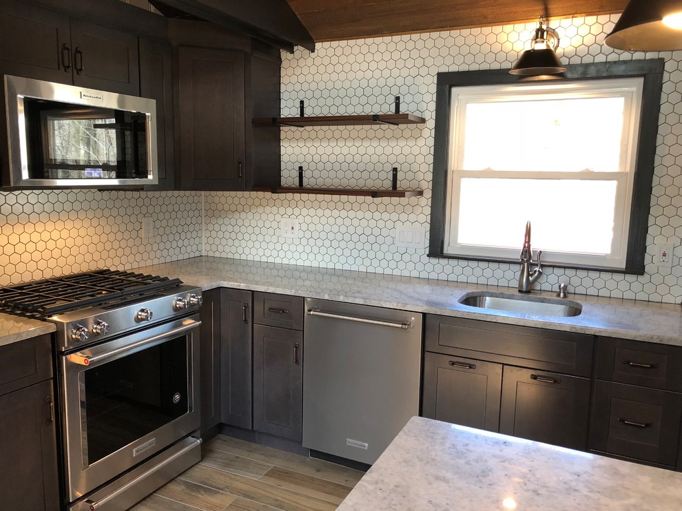 Example of a small eclectic galley porcelain tile and brown floor enclosed kitchen design in New York with an undermount sink, shaker cabinets, brown cabinets, granite countertops, white backsplash, ceramic backsplash, stainless steel appliances, a peninsula and white countertops