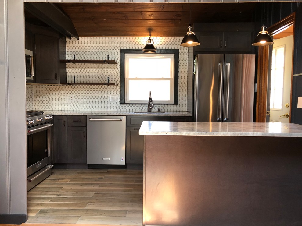 Exempel på ett avskilt, litet eklektiskt vit vitt parallellkök, med en undermonterad diskho, skåp i shakerstil, bruna skåp, granitbänkskiva, vitt stänkskydd, stänkskydd i keramik, rostfria vitvaror, klinkergolv i porslin, en halv köksö och brunt golv