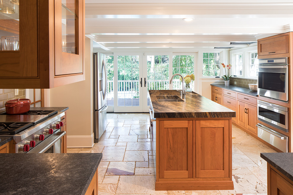 Inredning av ett klassiskt litet kök, med en undermonterad diskho, skåp i shakerstil, bruna skåp, marmorbänkskiva, grönt stänkskydd, stänkskydd i cementkakel, rostfria vitvaror, en köksö, flerfärgat golv och travertin golv
