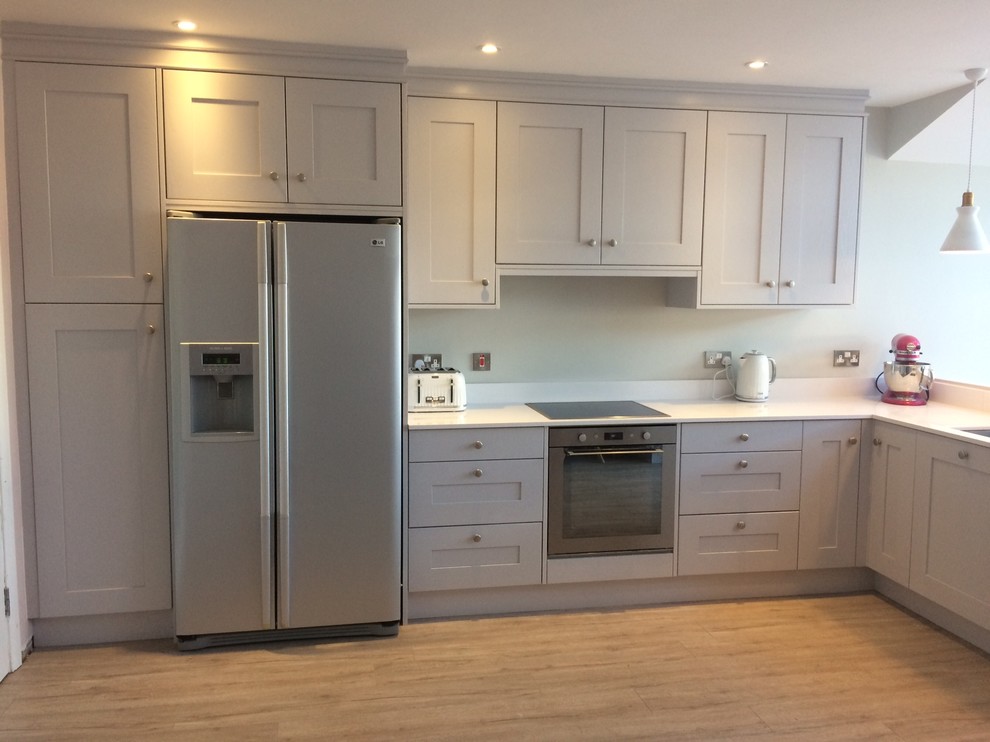 Example of a mid-sized transitional l-shaped light wood floor eat-in kitchen design in Dublin with an undermount sink, shaker cabinets, gray cabinets, quartzite countertops, stainless steel appliances and no island