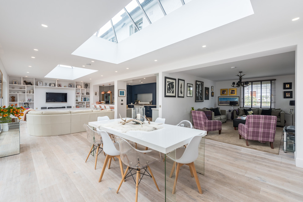 This is an example of a medium sized contemporary galley open plan kitchen in Edinburgh with an integrated sink, shaker cabinets, grey cabinets, composite countertops, grey splashback, glass sheet splashback, white appliances, medium hardwood flooring, a breakfast bar, brown floors and white worktops.