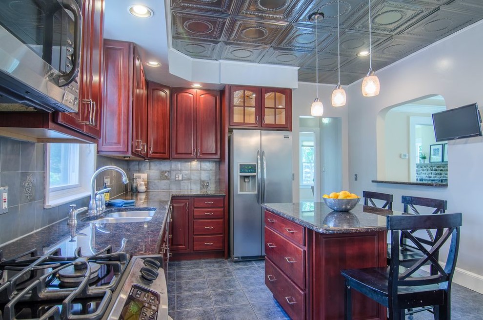 Exempel på ett mycket stort retro flerfärgad flerfärgat kök, med en dubbel diskho, luckor med upphöjd panel, bruna skåp, granitbänkskiva, stänkskydd med metallisk yta, stänkskydd i metallkakel, rostfria vitvaror, klinkergolv i porslin, en köksö och flerfärgat golv