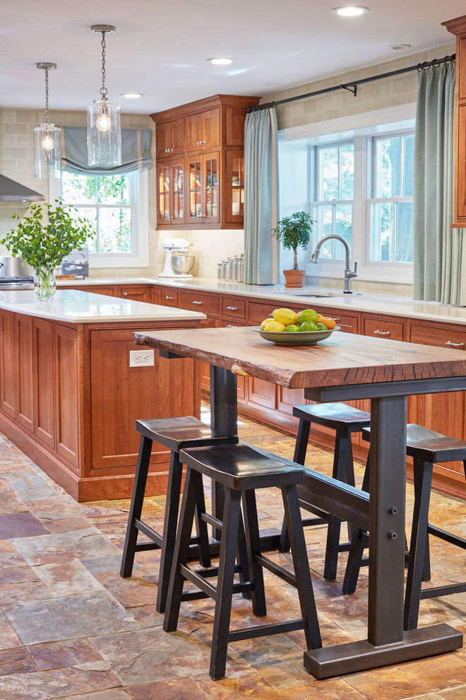 Eat-in kitchen - mid-sized rustic u-shaped ceramic tile eat-in kitchen idea in Baltimore with a double-bowl sink, raised-panel cabinets, light wood cabinets, solid surface countertops, white backsplash, subway tile backsplash, stainless steel appliances and an island