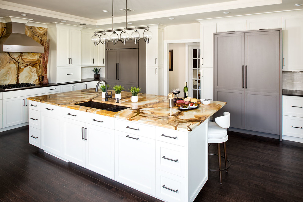 Foto på ett stort funkis kök, med en undermonterad diskho, skåp i shakerstil, vita skåp, granitbänkskiva, flerfärgad stänkskydd, stänkskydd i sten, integrerade vitvaror, mörkt trägolv och en köksö