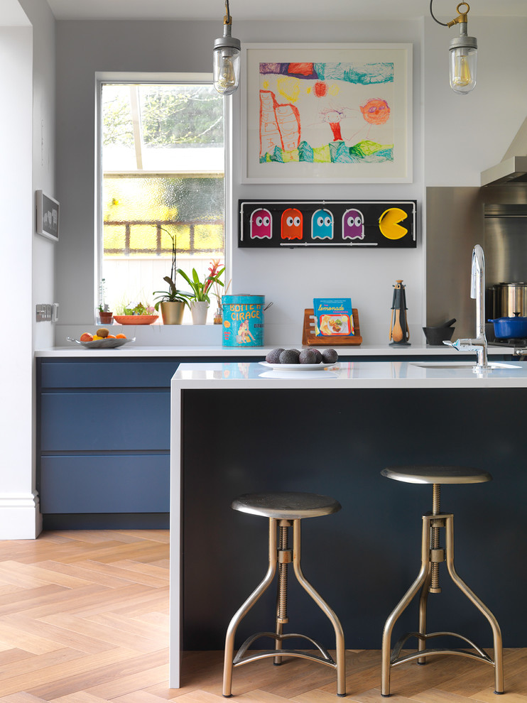 Offene Industrial Küche mit Waschbecken, flächenbündigen Schrankfronten, blauen Schränken, Küchengeräten aus Edelstahl, hellem Holzboden und Kücheninsel in London
