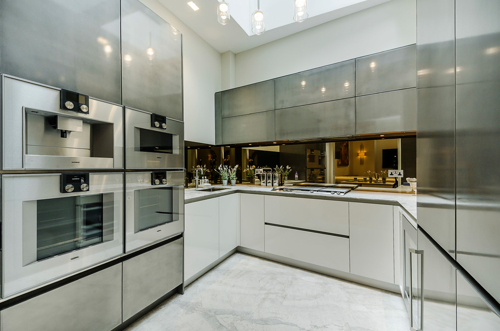 Photo of a large contemporary u-shaped open plan kitchen in London with a submerged sink, flat-panel cabinets, marble worktops, mirror splashback, stainless steel appliances, no island and white floors.