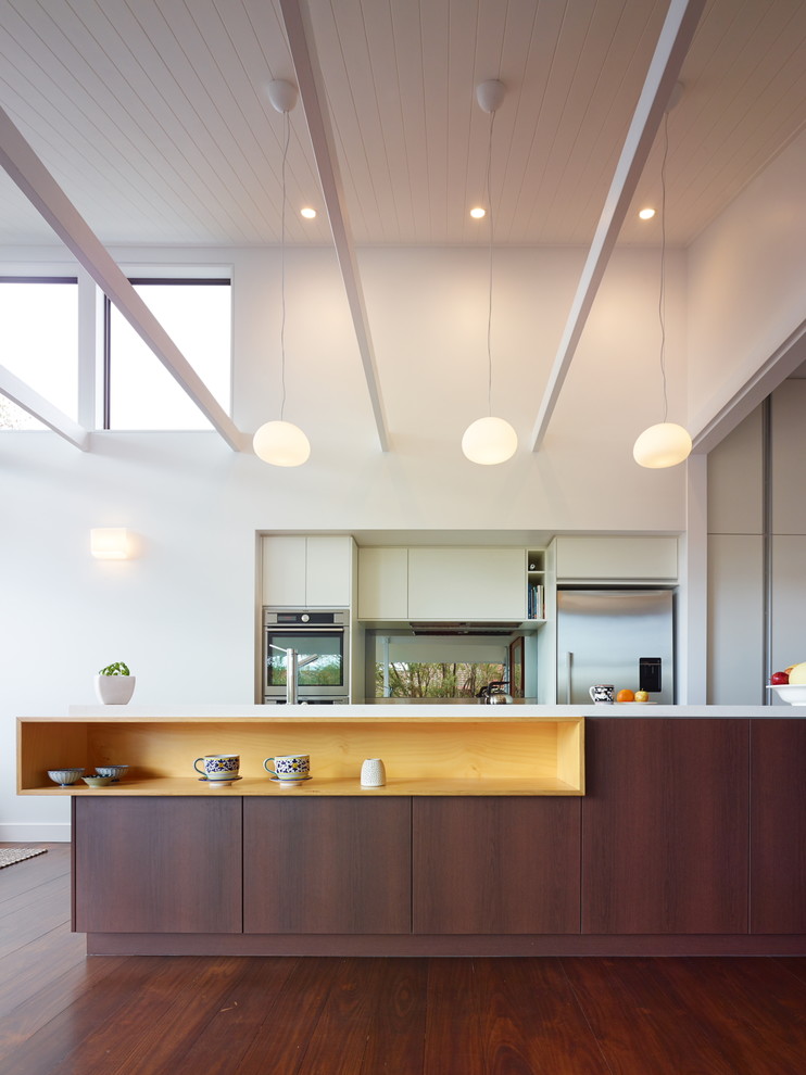 Zweizeilige, Mittelgroße Moderne Wohnküche mit Küchengeräten aus Edelstahl, Kücheninsel, flächenbündigen Schrankfronten, dunklen Holzschränken und dunklem Holzboden in Brisbane