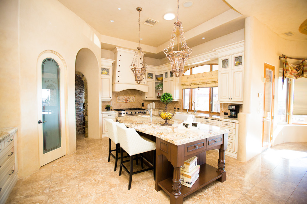 Inspiration for a mediterranean u-shaped kitchen in Phoenix with a belfast sink, raised-panel cabinets, beige cabinets, beige splashback, an island and beige floors.