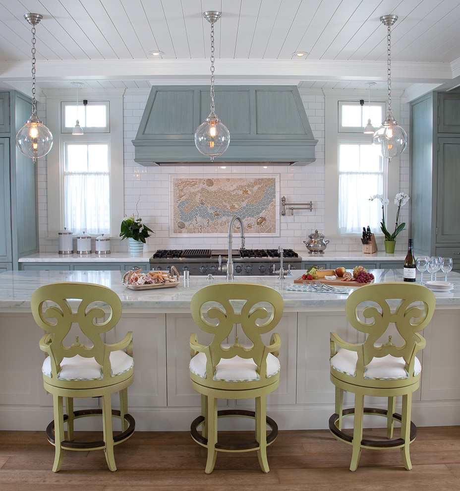Exempel på ett stort maritimt kök, med en nedsänkt diskho, luckor med profilerade fronter, blå skåp, marmorbänkskiva, flerfärgad stänkskydd, stänkskydd i keramik, rostfria vitvaror, mellanmörkt trägolv och en köksö