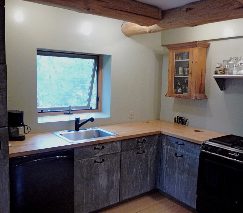 Foto di una cucina a L rustica chiusa e di medie dimensioni con lavello da incasso, ante lisce, ante grigie, top in legno, elettrodomestici neri e parquet chiaro