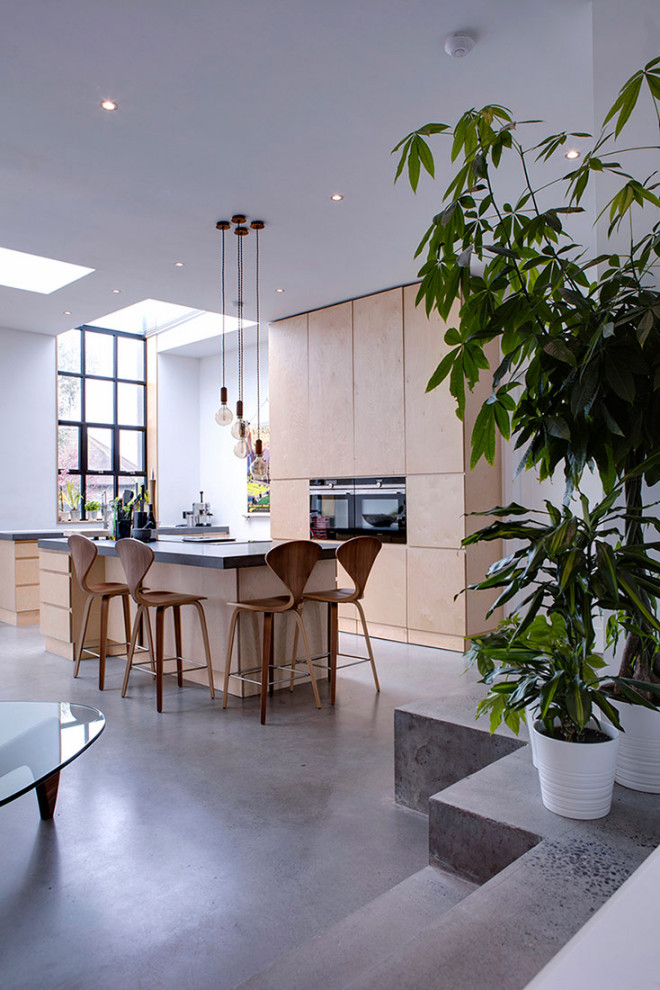 Medium sized scandinavian kitchen/diner in Dublin with a built-in sink, flat-panel cabinets, light wood cabinets, concrete worktops, concrete flooring, an island and black worktops.