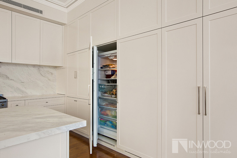 Diseño de cocina minimalista con armarios estilo shaker, puertas de armario blancas, encimera de mármol y una isla