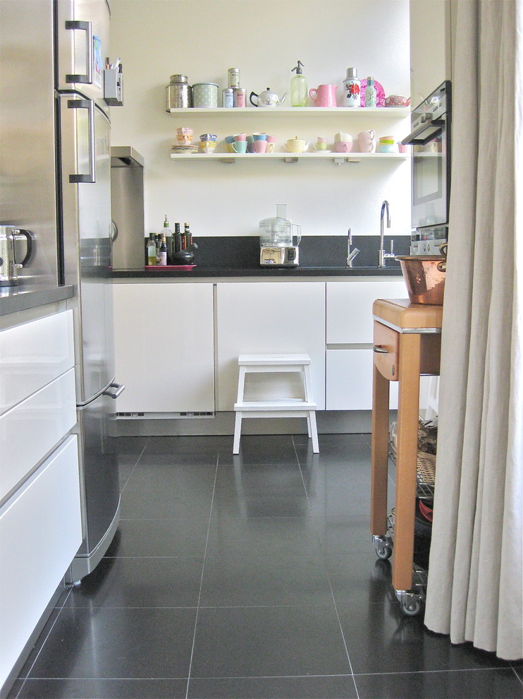 Example of a minimalist kitchen design in Amsterdam with flat-panel cabinets, white cabinets and stainless steel appliances