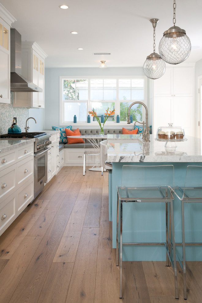 Design ideas for a large beach style l-shaped kitchen/diner in Los Angeles with a belfast sink, shaker cabinets, white cabinets, blue splashback, mosaic tiled splashback, stainless steel appliances, medium hardwood flooring, an island, beige floors and quartz worktops.