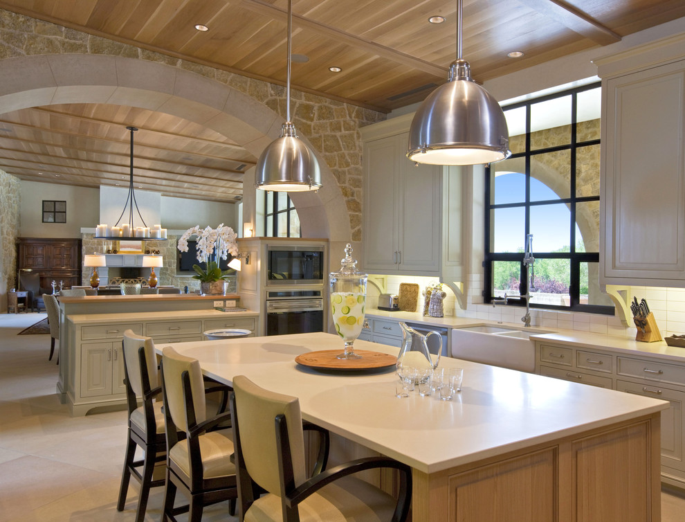 Open concept kitchen - large contemporary u-shaped limestone floor open concept kitchen idea in Austin with raised-panel cabinets, a double-bowl sink, white cabinets, stainless steel appliances, an island, solid surface countertops, white backsplash and subway tile backsplash