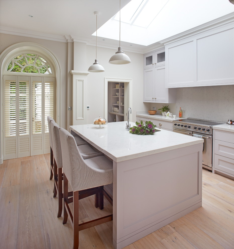 Example of a mid-sized classic light wood floor kitchen design in Dublin with shaker cabinets, gray cabinets, solid surface countertops, stainless steel appliances and an island