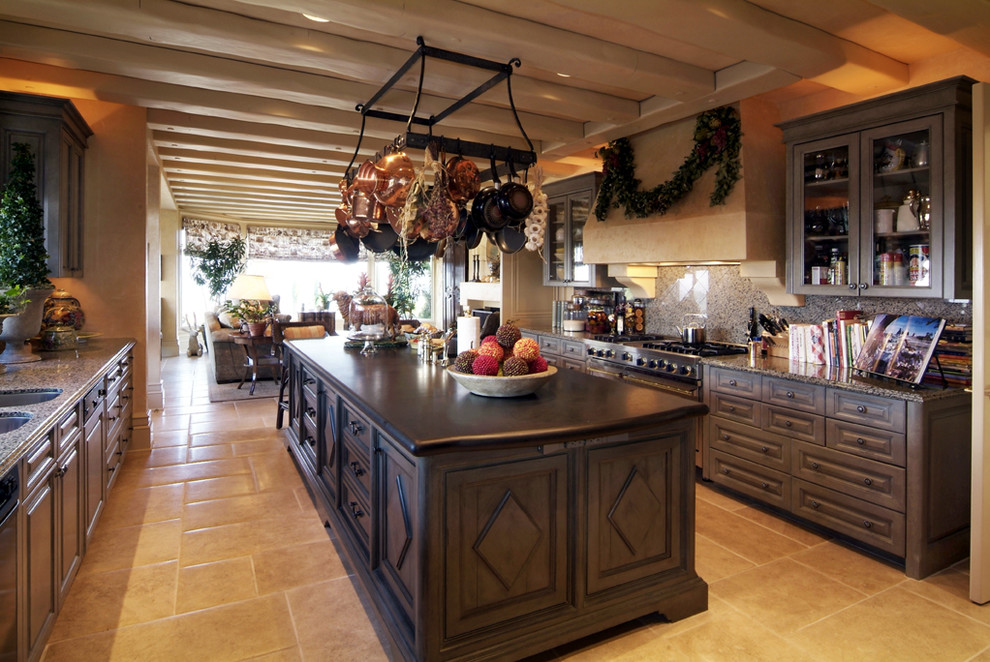 Exempel på ett medelhavsstil kök, med en undermonterad diskho, luckor med infälld panel, skåp i slitet trä, granitbänkskiva, stänkskydd i stenkakel, rostfria vitvaror, travertin golv och en köksö