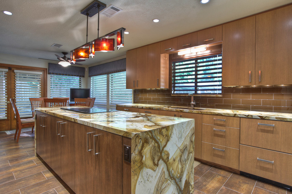 Cette photo montre une cuisine américaine encastrable et parallèle moderne en bois brun avec un évier encastré, un placard à porte plane, un plan de travail en granite, une crédence marron et une crédence en carreau de verre.