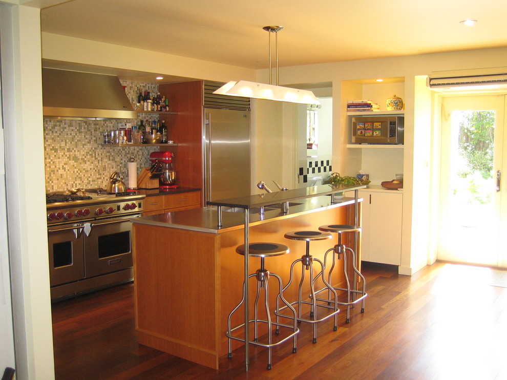 ニューヨークにあるコンテンポラリースタイルのおしゃれなII型キッチン (フラットパネル扉のキャビネット、中間色木目調キャビネット、ステンレスカウンター、マルチカラーのキッチンパネル、モザイクタイルのキッチンパネル、シルバーの調理設備) の写真