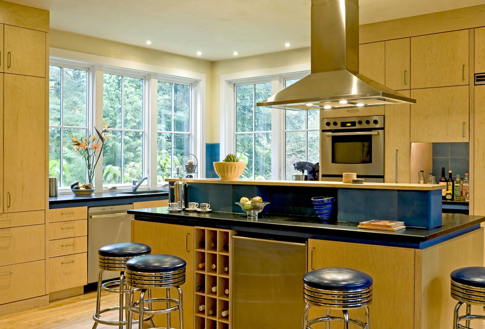 Esempio di una cucina design con elettrodomestici in acciaio inossidabile, ante lisce e ante in legno chiaro