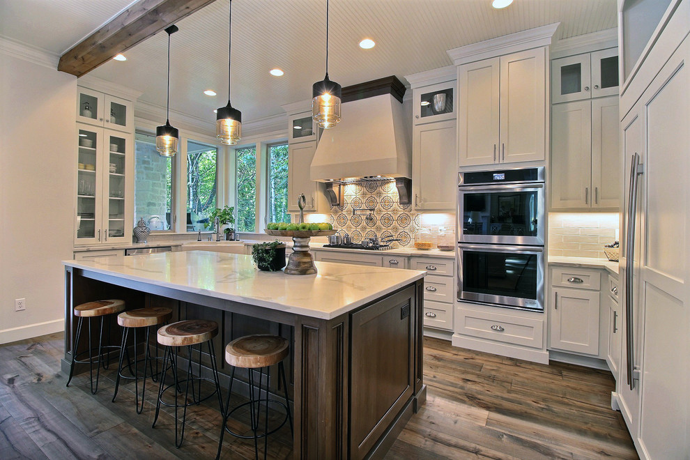 Example of a huge arts and crafts u-shaped dark wood floor and brown floor open concept kitchen design in Portland with a farmhouse sink, recessed-panel cabinets, white cabinets, quartz countertops, multicolored backsplash, ceramic backsplash, paneled appliances and an island