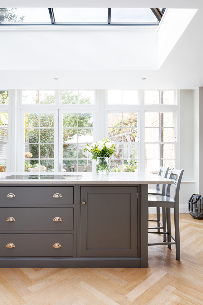 Mittelgroße Klassische Küche mit Schrankfronten mit vertiefter Füllung, grauen Schränken, hellem Holzboden, Kücheninsel und beigem Boden in London