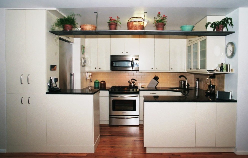 Inredning av ett modernt avskilt, mellanstort u-kök, med en undermonterad diskho, släta luckor, skåp i ljust trä, granitbänkskiva, beige stänkskydd, stänkskydd i keramik, rostfria vitvaror, klinkergolv i keramik och en halv köksö