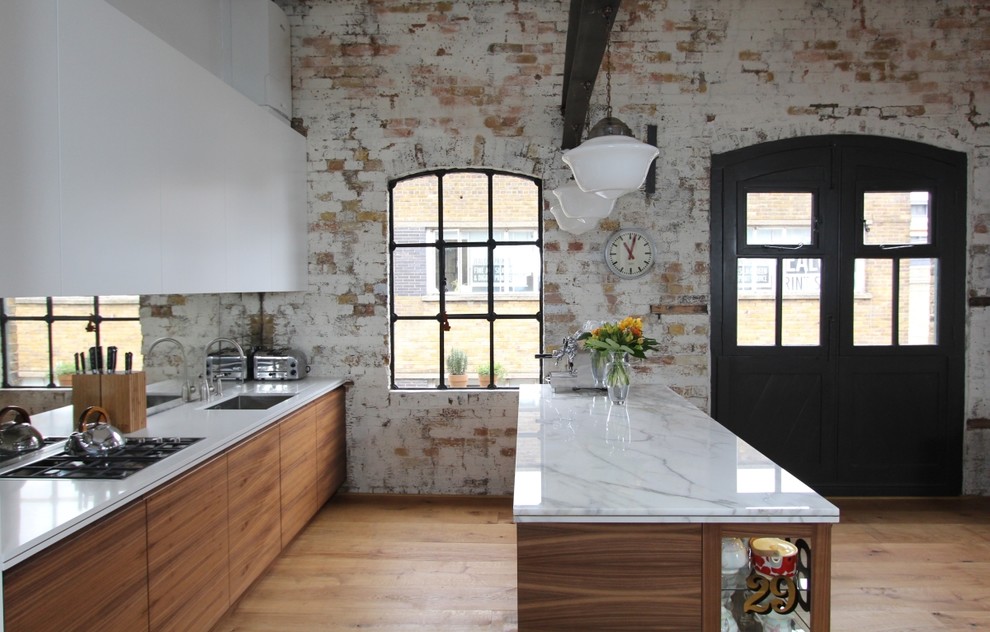 Photo of a large contemporary single-wall open plan kitchen in London with a submerged sink, flat-panel cabinets, medium wood cabinets, marble worktops, metallic splashback, glass sheet splashback, stainless steel appliances, medium hardwood flooring and an island.