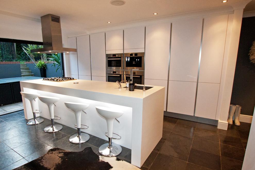 Example of a large minimalist kitchen design in London with white cabinets and an island