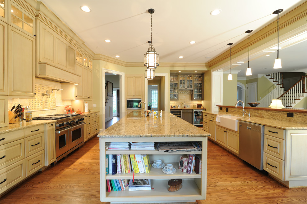 Inspiration for a large timeless galley dark wood floor and brown floor open concept kitchen remodel in Raleigh with a farmhouse sink, raised-panel cabinets, beige cabinets, granite countertops, beige backsplash, stone tile backsplash, stainless steel appliances and two islands