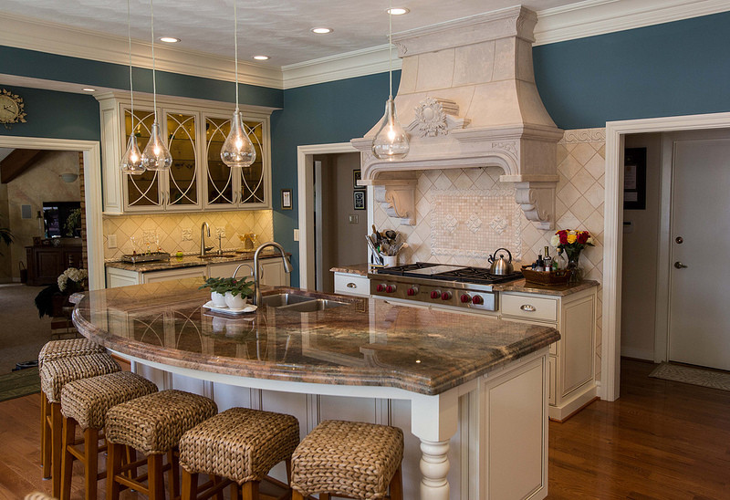 Exempel på ett stort medelhavsstil kök, med en undermonterad diskho, luckor med infälld panel, vita skåp, granitbänkskiva, beige stänkskydd, stänkskydd i keramik, rostfria vitvaror, mellanmörkt trägolv och en köksö