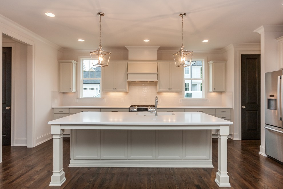 Exempel på ett avskilt, stort modernt l-kök, med en undermonterad diskho, luckor med infälld panel, vita skåp, bänkskiva i kvarts, vitt stänkskydd, stänkskydd i mosaik, rostfria vitvaror, mörkt trägolv och en köksö