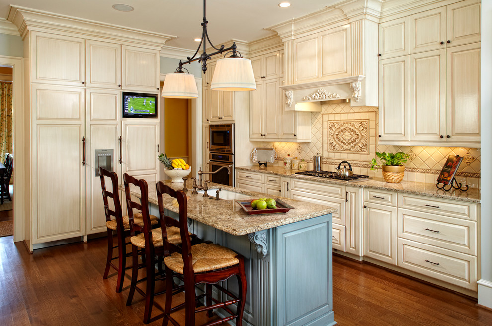 Open concept kitchen - mid-sized traditional single-wall medium tone wood floor open concept kitchen idea in Other with an undermount sink, raised-panel cabinets, beige cabinets, granite countertops, beige backsplash, ceramic backsplash, stainless steel appliances and an island