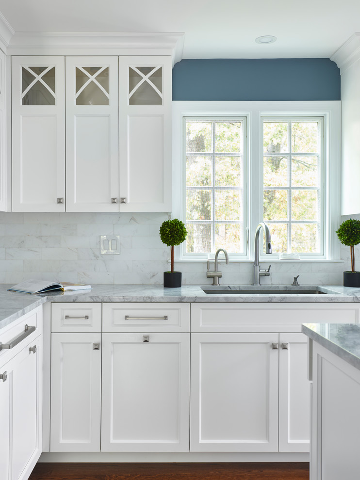 Foto på ett vintage grå l-kök, med en undermonterad diskho, skåp i shakerstil, vita skåp, marmorbänkskiva, vitt stänkskydd, stänkskydd i marmor, en köksö, mörkt trägolv och brunt golv