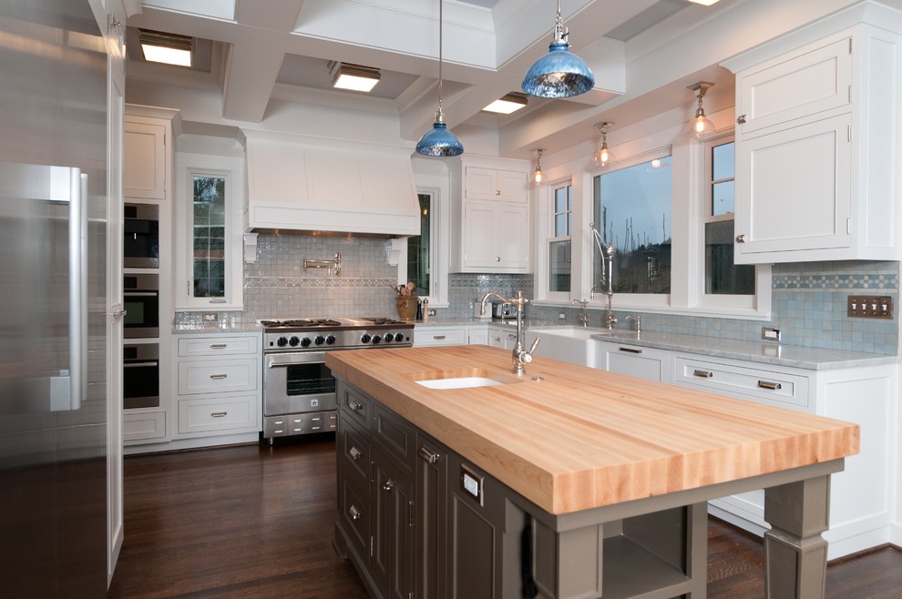 Example of a classic kitchen design in Portland with shaker cabinets, stainless steel appliances, wood countertops, a farmhouse sink, white cabinets and blue backsplash