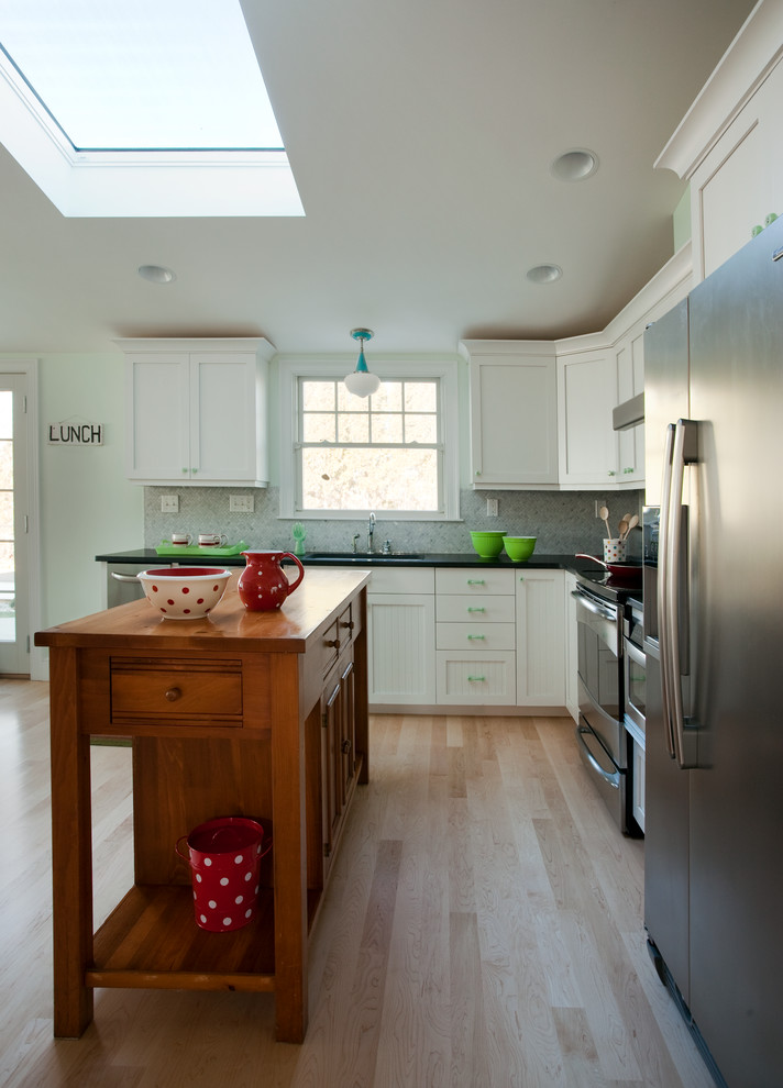 Example of a beach style l-shaped eat-in kitchen design in Providence with an undermount sink, recessed-panel cabinets, white cabinets, granite countertops, multicolored backsplash, glass tile backsplash and stainless steel appliances