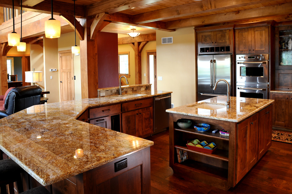 Example of a mid-sized mountain style u-shaped dark wood floor eat-in kitchen design in Other with an integrated sink, recessed-panel cabinets, dark wood cabinets, granite countertops, stone tile backsplash, stainless steel appliances and an island
