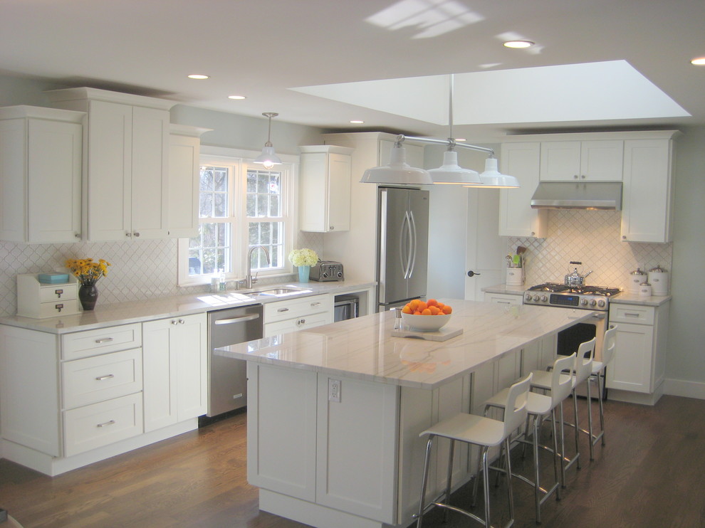 Eat-in kitchen - mid-sized transitional l-shaped medium tone wood floor eat-in kitchen idea in New York with a double-bowl sink, shaker cabinets, white cabinets, quartzite countertops, white backsplash, porcelain backsplash, stainless steel appliances and an island