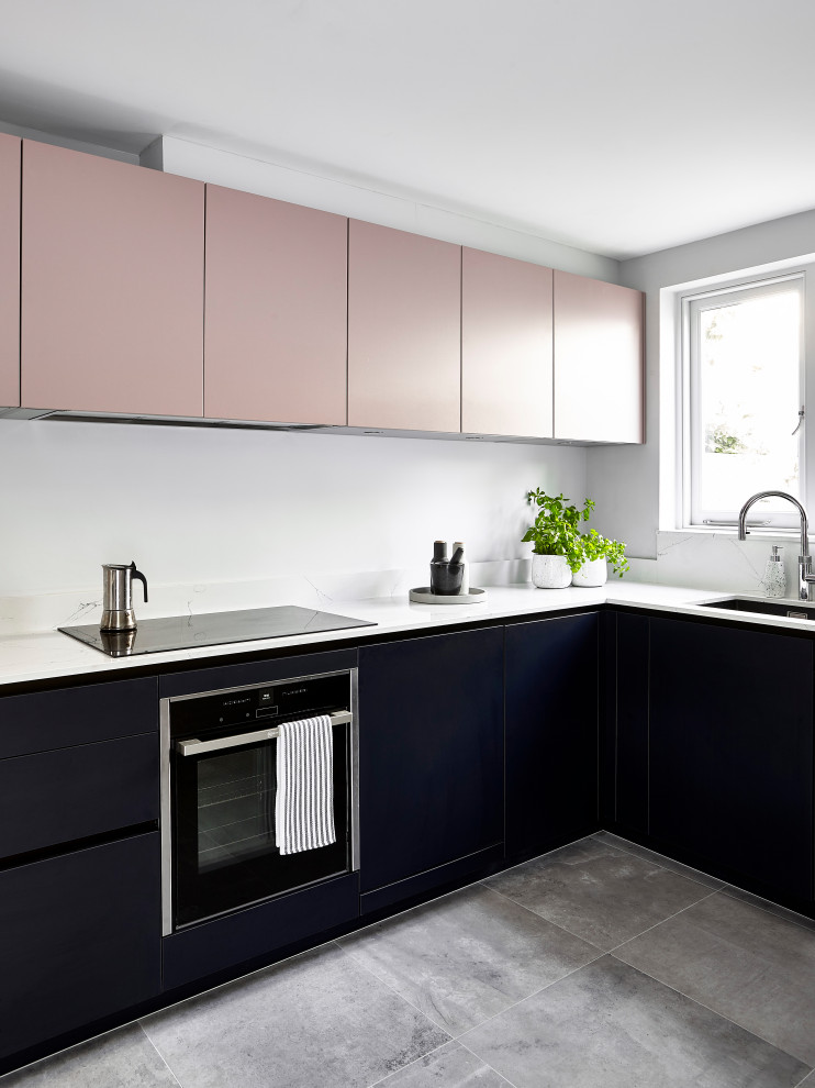 Imagen de cocinas en L contemporánea con fregadero bajoencimera, armarios con paneles lisos, puertas de armario negras, electrodomésticos de acero inoxidable, suelo gris y encimeras blancas