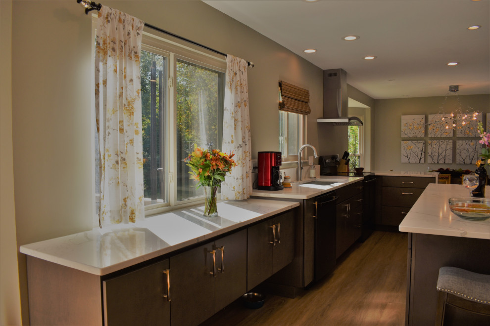 Foto di una cucina design di medie dimensioni con lavello sottopiano, ante lisce, ante grigie, top in quarzo composito, elettrodomestici neri, pavimento in laminato, pavimento marrone e top bianco