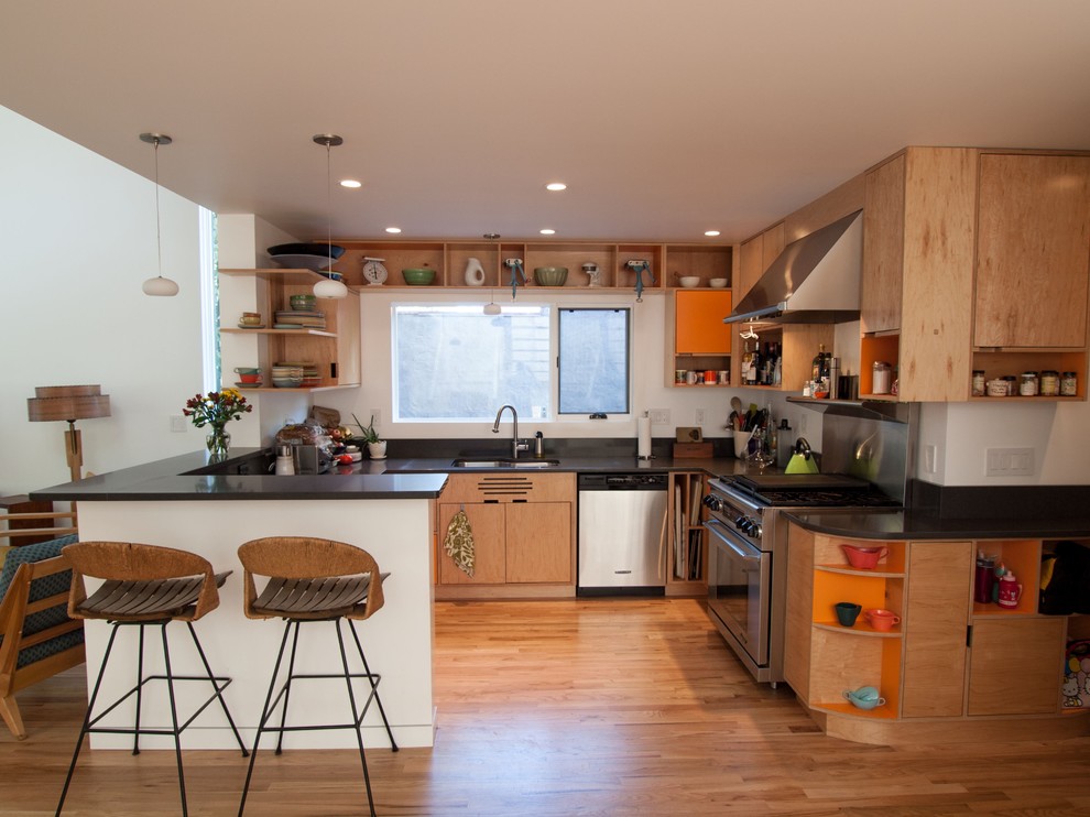 Example of a minimalist kitchen design in Portland with stainless steel appliances, open cabinets and light wood cabinets