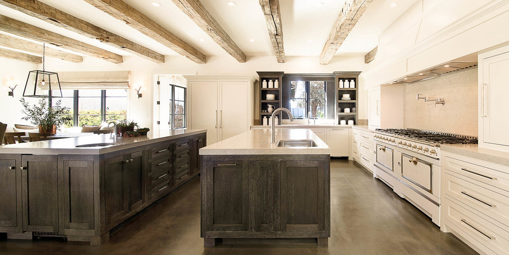 Huge cottage u-shaped concrete floor and brown floor eat-in kitchen photo in San Francisco with an undermount sink, shaker cabinets, white cabinets, beige backsplash, two islands, white appliances, quartz countertops and stone slab backsplash